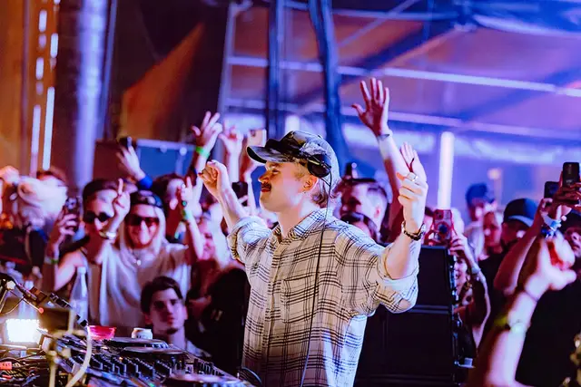 A DJ with hands up over the crowd at III Points 2025